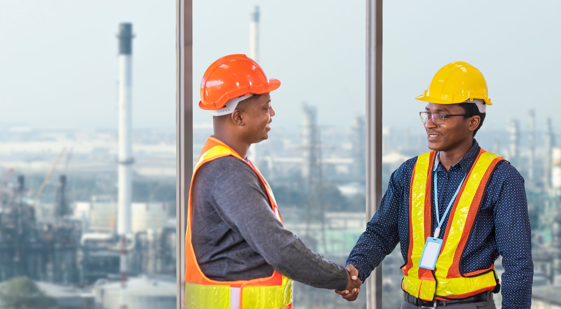 African American engineer and security team handshaking for agreement in partnership project for petroleum and crude oil refinery factory for power industry concept